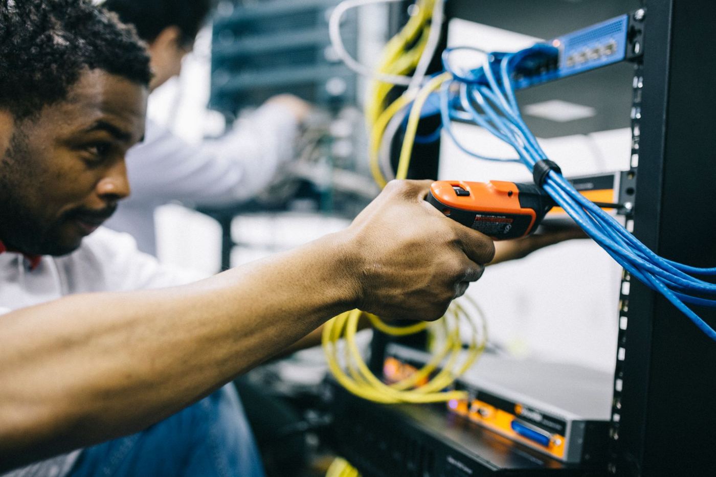 Technician running blue network cable into a rack